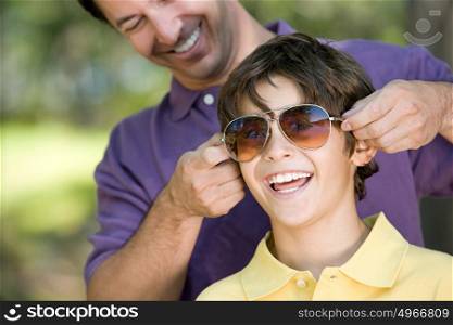 Father putting sunglasses on son