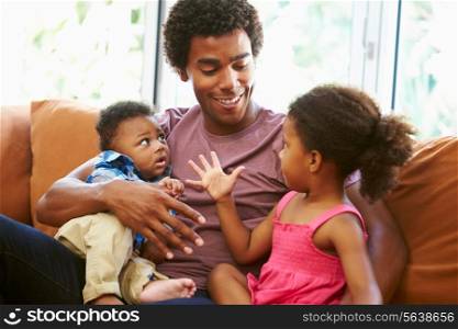 Father Relaxing On Sofa With Young Children