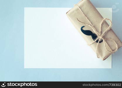 Father's day. Gift package wrapped with paper and rope on light blue background. Copyspace. Top view. Father's day. White card and Gift package wrapped with paper and rope on light blue background. Copyspace