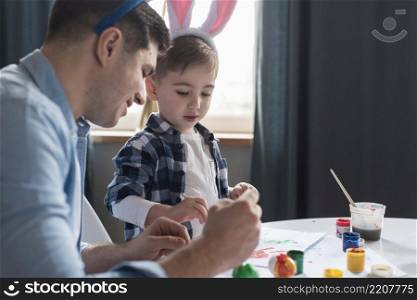 father showing his son how paint easter eggs