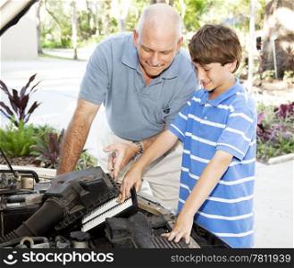 Father shows his son how to put a clean air filter in the car engine.