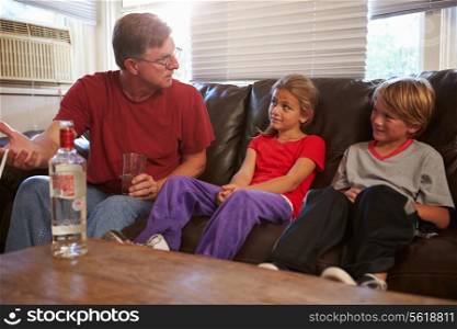 Father Sits On Sofa With Children Smoking And Drinking