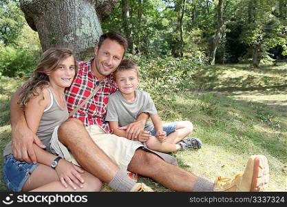 Father sitting by a tree with his children