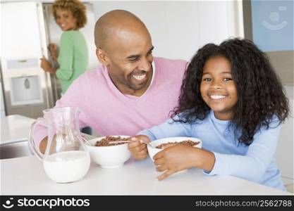 Father Sitting With Daughter As She They Eat Breakfast With Her Mother In The Background