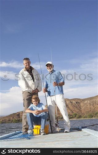 Father son and grandson sit with fishing equipment on a pier
