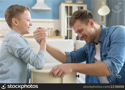 father son doing arm wrestling indoors