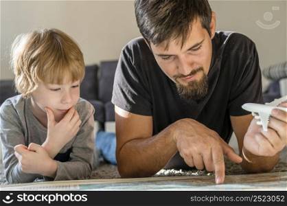 father son looking map together home