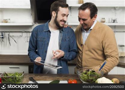 father son looking tablet kitchen