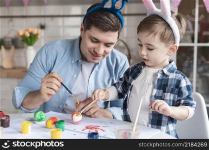 father son painting eggs easter together