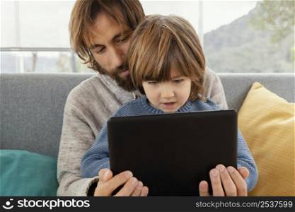 father son playing together with tablet
