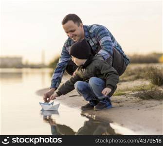 father son playing with origami boat