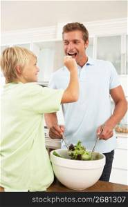 Father & Son Preparing Salad In Modern Kitchen