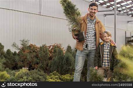 father son together tree nursery posing with pot