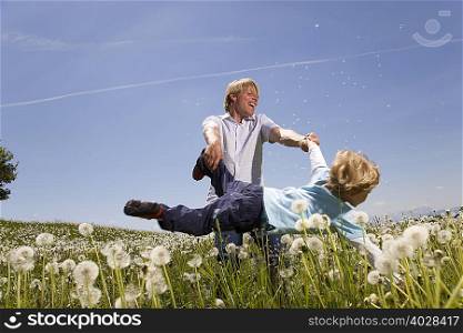 father swinging son in meadow