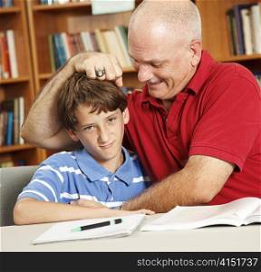 Father takes a break from helping his son with homework to give him noogies.