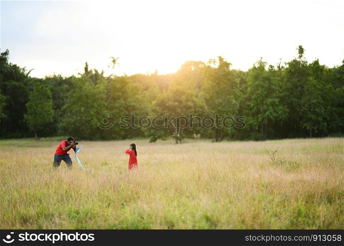 father takes a photo of his daughter in the garden,field, evening, sunset, family time, warm feeling