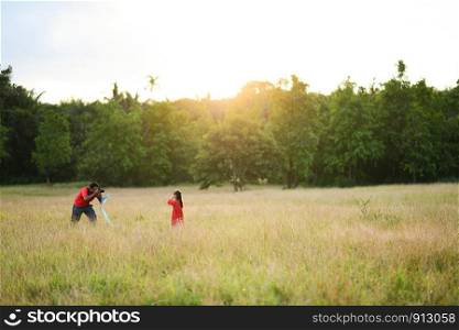 father takes a photo of his daughter in the garden,field, evening, sunset, family time, warm feeling