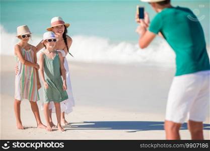 Father taking a photo on their beach vacation. Family of four taking a selfie photo on their beach holidays.