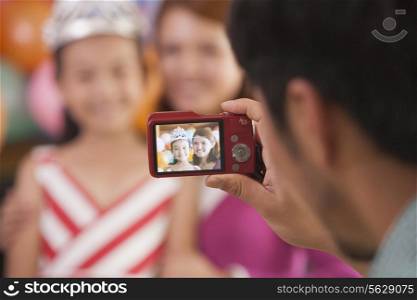 Father Taking a Picture of Mother and Daughter on Daughter&rsquo;s Birthday
