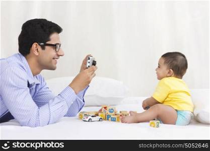 Father taking picture of baby playing