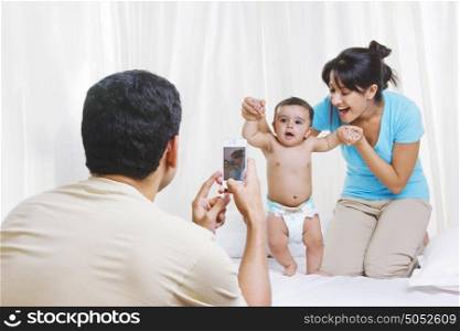 Father taking picture of mother and baby