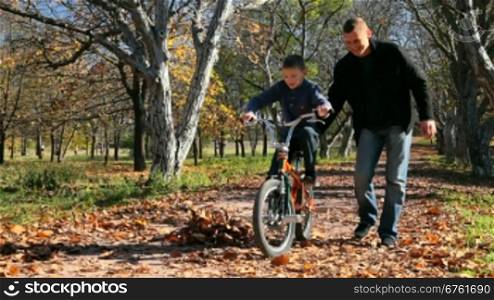 father teaches his son to ride a bicycle in the park