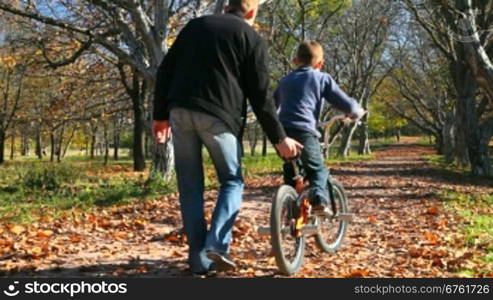 father teaches his son to ride a bicycle in the park