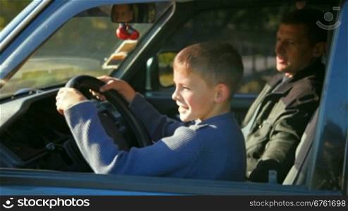 father teaches son to drive car