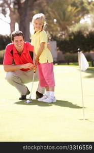 Father Teaching Daughter To Play Golf On Putting On Green