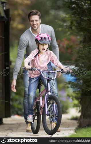 Father Teaching Daughter To Ride Bike In Garden