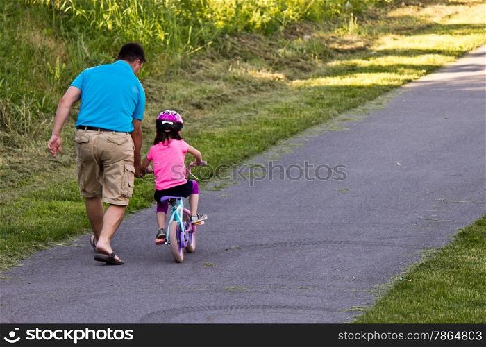Father teaching daughter to ride her bike