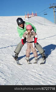 Father Teaching Daughter To Ski Whilst On Holiday In Mountains