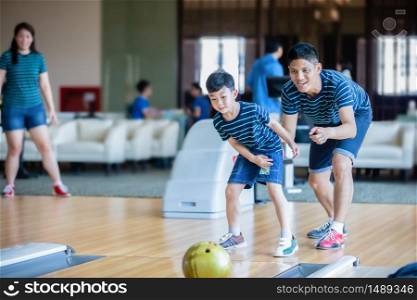 Father teaching son and family play bowling at bowling club on relax time, family activity on holiday concept