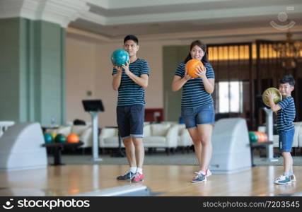 Father teaching son and family play bowling at bowling club on relax time