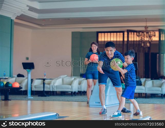 Father teaching son and family play bowling at bowling club on relax time