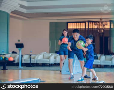 Father teaching son and family play bowling at bowling club on relax time