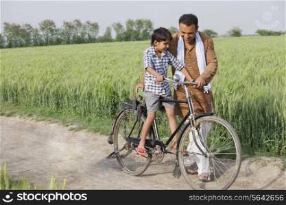 Father teaching son how to ride cycle