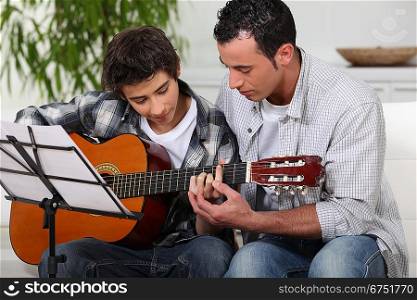 Father teaching son the guitar