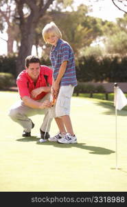 Father Teaching Son To Play Golf On Putting On Green