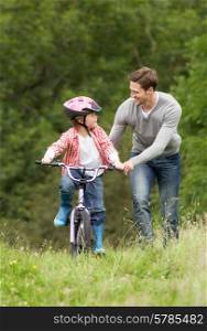 Father Teaching Son To Ride Bike In Countryside