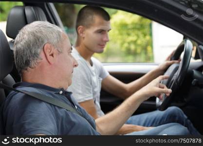 father teaching teenage son to drive