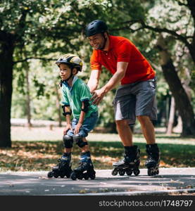 Father teching son roller skating in park
