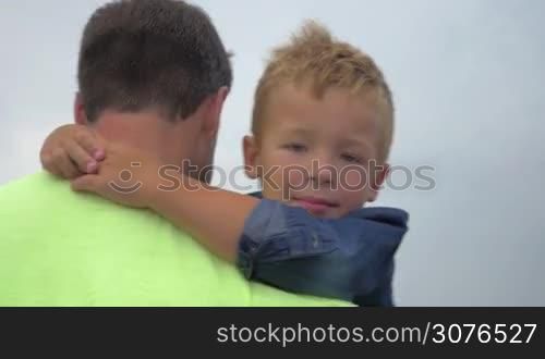 Father walks and keeps in arms his little son. Family walk on the street. Son&acute;s face close-up