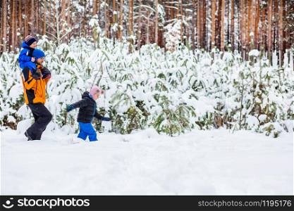 Father walks with his young children in the woods in winter. Winter activities in the snow, sleds and snowballs. Father walks with his young children in the woods in winter.