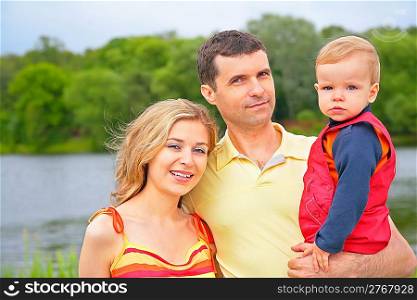 father with child on hands and mother outdoors