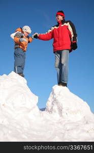 father with child stand on snow hill