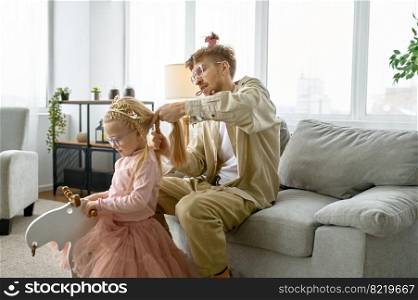 Father with crazy hairstyle and mad face grimace making hair for daughter, happy parenting. Father with crazy hairstyle making hair for daughter