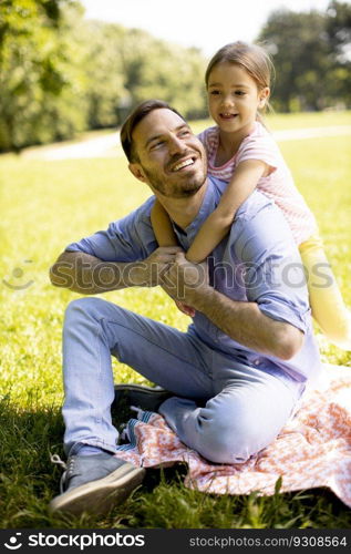 Father with cute little daughter having fun on the grass at the park