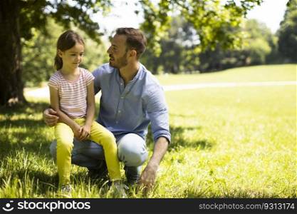 Father with cute little daughter having fun on the grass at the park