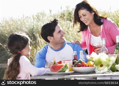 Father With Daughter And Grandmother Enjoying Outdoor Barbeque